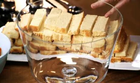 Cake in reepjes gesneden voor tiramisu-koekjes, achter een glas